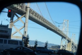 The bridge seen in my side-view mirror as I wait at a traffic light on my way out of the city (San Francisco, California).